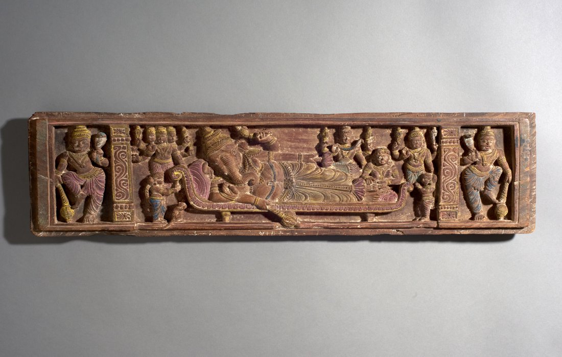 Indian Wood Carving of Ganesh: India, ca. 19th century. An interesting and unusual scene with Ganesh reclining and surrounded by deities and attendants. Charming. Length: 30 inches / 76 cm