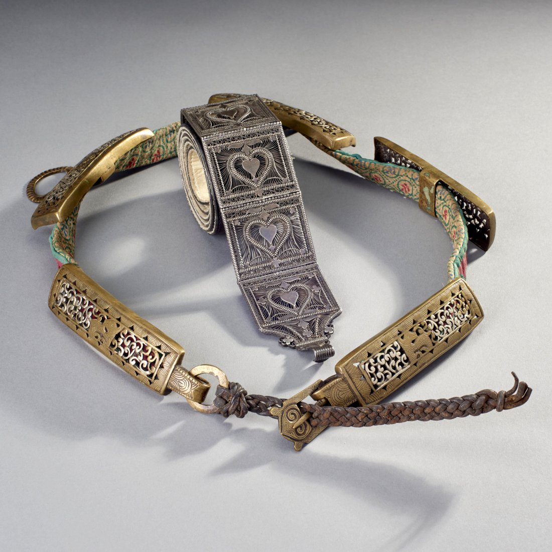 Two Asian Belts: Tibet and India, ca. 19th-early 20th century. Two belts, the first a fine Tibetan belt with bronze panels, the centers carved in openwork silver, the Indian belt with five silver filigree panels attac