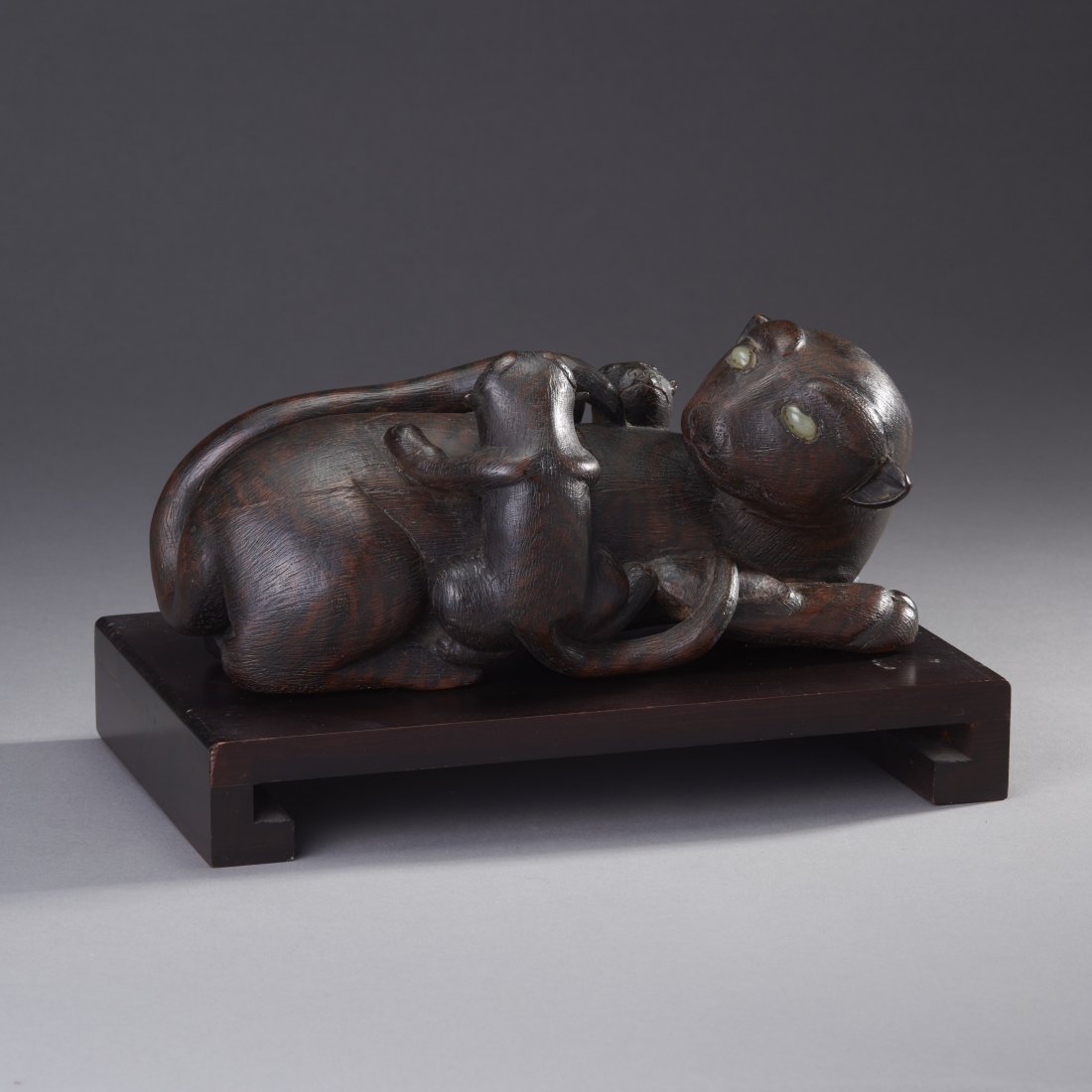 Korean Wood Tigers: Korea or Japan, ca. 19th century. Carved wooden tigers.A charming tableau of mother cat with cubs, decorated with all-over striping and cabochon eyes. Signature plaque below. On stand. Length: 9.5 inc