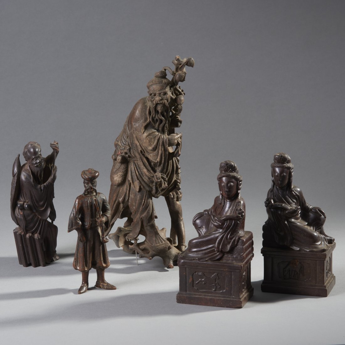 Five Asian Carved Figures: Consisting of a pair of Chinese stone deities, two Chinese wood figures, and a possibly Central Asian wood figure. Provenance: Old Connecticut Estate Height of tallest: 12 inches / 30.5 cm