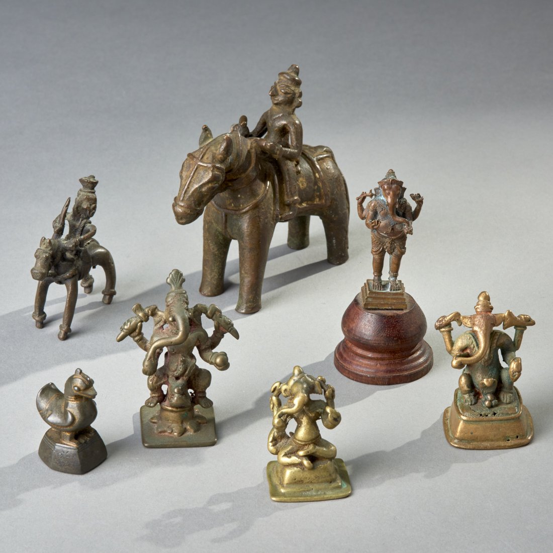 Seven small Indian bronzes: India, ca. 18th - 19th century. Consistng of two equestrian figures, four Ganeshes and a Burmese opium weight. Height of tallest: 4 inches / 10.2 cm