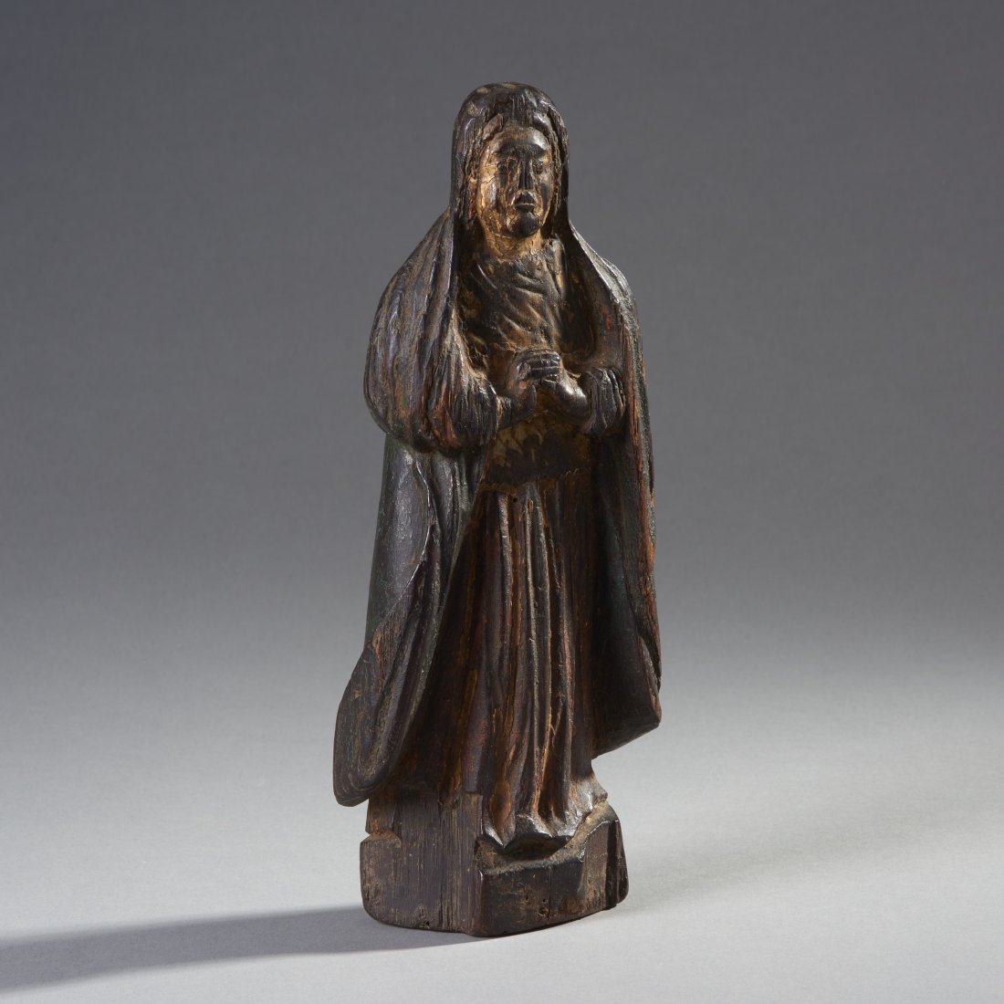 Goanese Wooden Saint: Goa, ca. 18th century. Carved wooden saint, the standing robed figure with hands clasped and flat back. Height: 11.8 inches / 29.8 cm