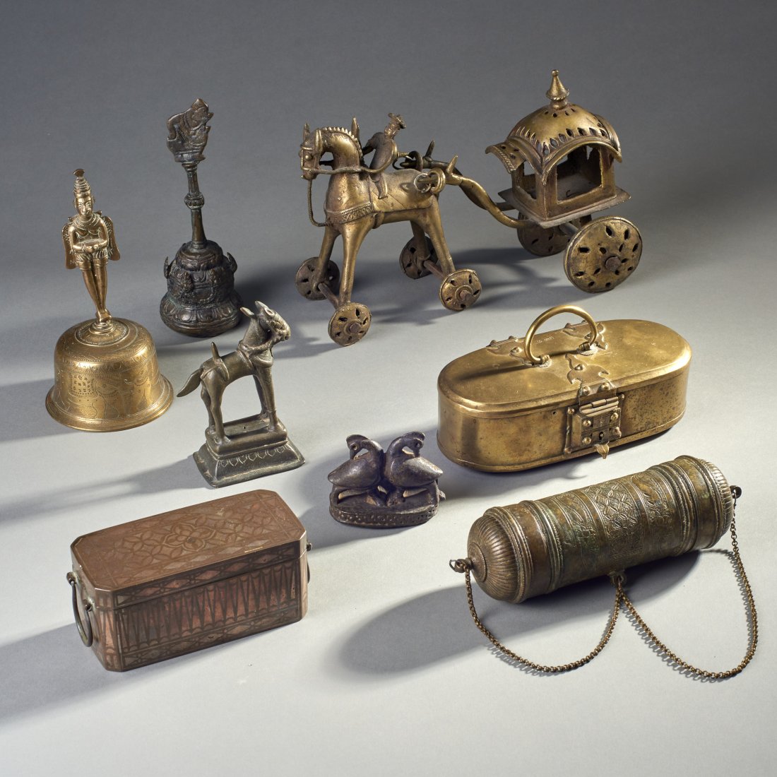 Eight Indian Bronzes: India and Indonesia, ca. 19th century. Eight bronze figures, consisting of two hand bells, a foot scraper/ rattle, an inlaid lime box, a cylindrical lime container, a large temple toy horse and cart, 