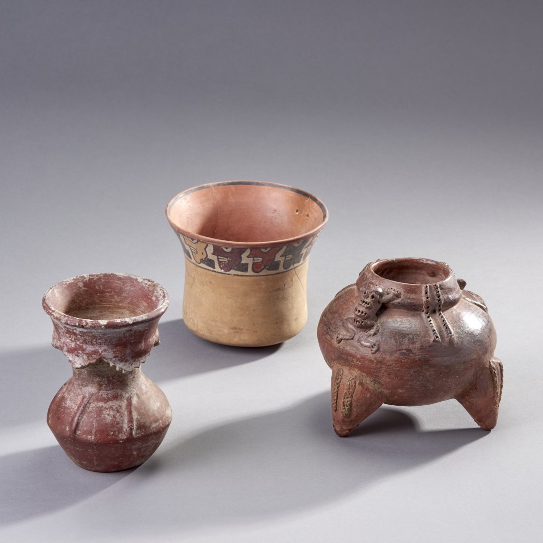 Three Pre-Columbian Vessels: Central and South America, ca. 1st millennium AD. Three Pre-Columbian vessels, consisting of a tripod bowl with human and frog decoration, an unusual small vase with an unusual skirted lip, and lastly