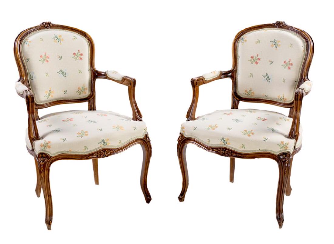 Pair of armchairs: in Louis XV taste walnut with molded cornices surmounted by flowered reliefs; shaped backs and upholstered seats covered with flower fabric, slightly shaped legs. 19th century, 87x56x50 cm
