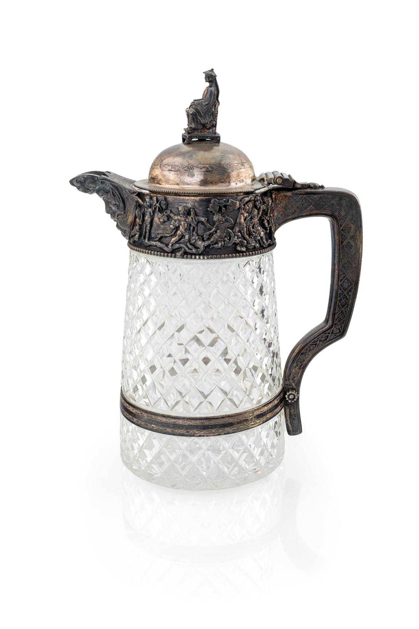 Crystal and silver tankard: con coperchio a cupolino sormontato dalla figura di dignitario seduto; versatoio sbalzato con mascherone e fascia decorata da un corteo di amorini.altezza cm 26