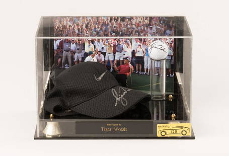 Tiger Woods Signed Hat and Golf Ball: Black Nike cap and golf ball hand signed by Tiger Woods, presented in a display case with a backdrop photo of Tiger celebrating in front of a crowd of fans. Includes Certificate of Authenticity.