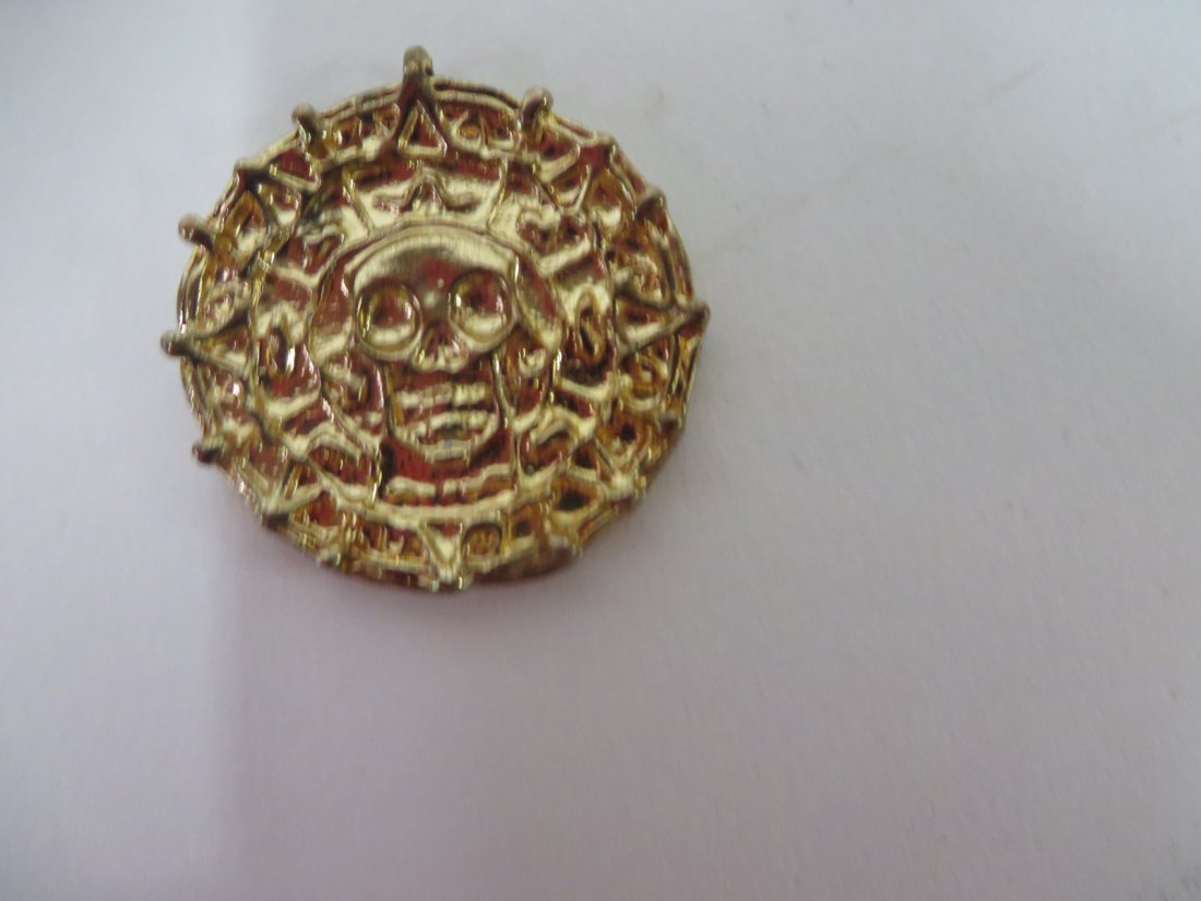 Film Prop. Pirates of the Caribbean Coin: Gold plated treasure coin. With letter C. Bailey dated 9/28/14.
