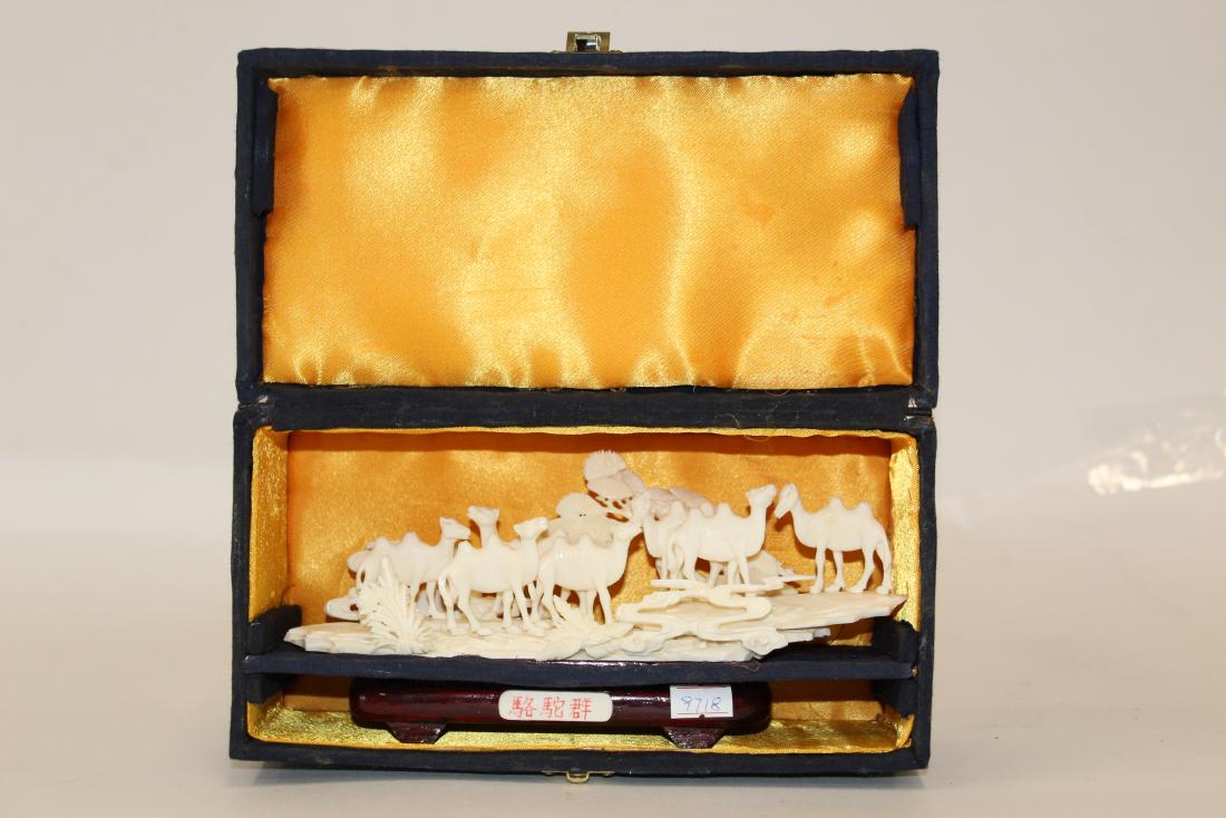 Carved Bone Camel Grouping: On mahogany stand. 2 1/2"H. x 8 3/4"W.