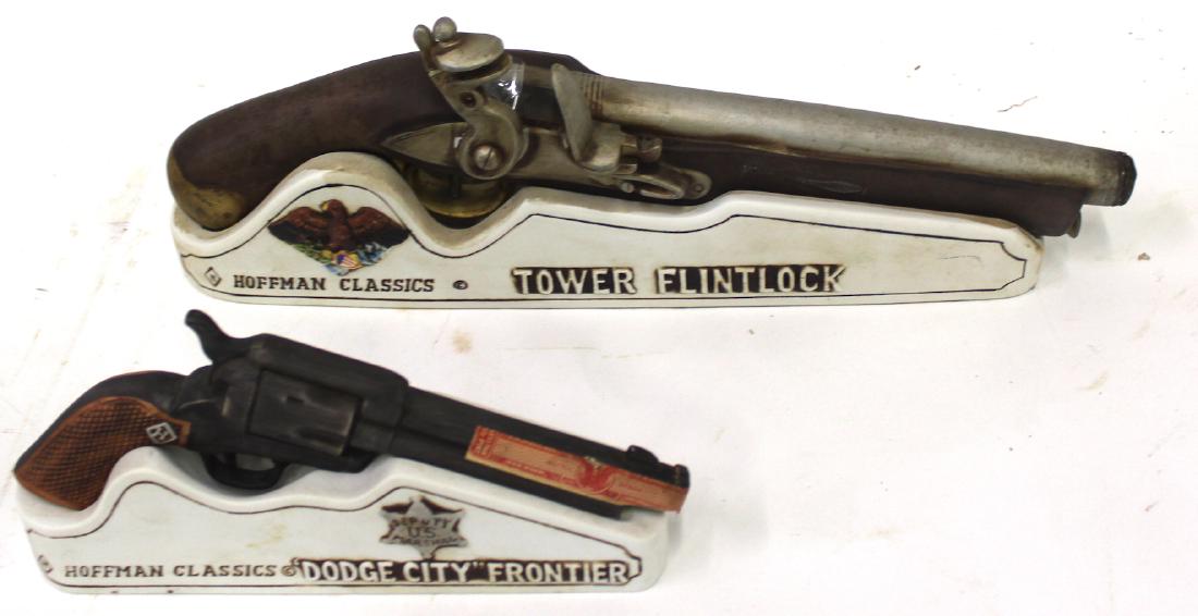 Hoffman Classics Pistol Decanters (2): Hoffman Classics Whiskey Decanters. Two pistols titled "Dodge City Frontier" and "Tower Flintlock" marked 1975. Came with stands that give facts about the pistols. 4.5" x 9" and 4" x 16"