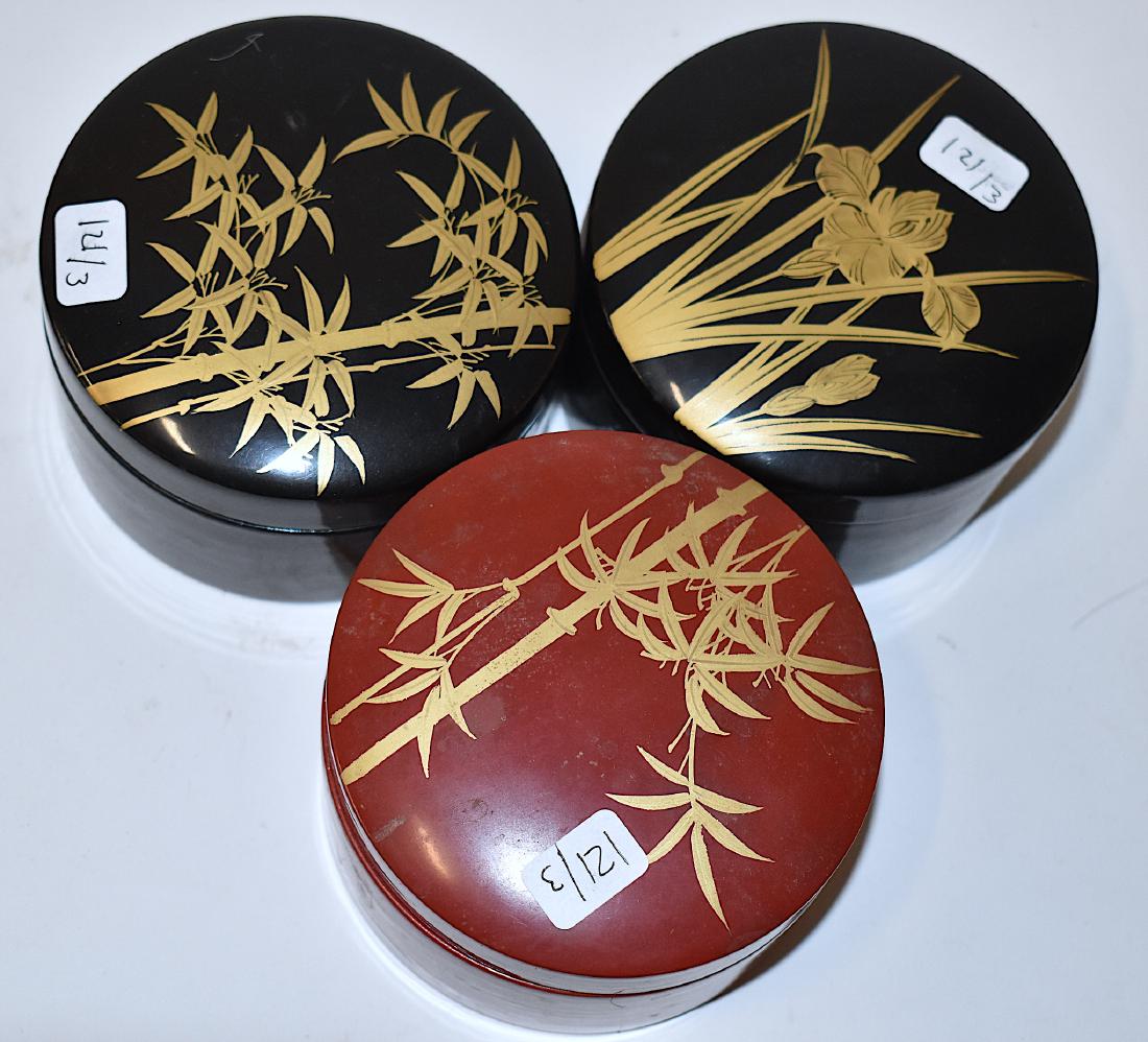 Japanese. Lacquered Boxes. Coasters at Inside. (3): Japanese Lacquered Boxes, each with coasters at the inside matching the top of the box. Two black lacquered boxes decorated with shoots and flowers as well as bamboo shoots and one red box decorated w