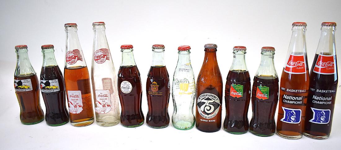Rare Coca Cola Commemorative Bottle Lot (12): Twelve in the lot. Two are 1991 Basketball National Champs Duke bottles; 34th Annual Convention, Dallas, 2008 Coca Cola Collectors Club; two from July 1993, Dearborn Mich 19th Annual Conv.; 75th Anniv