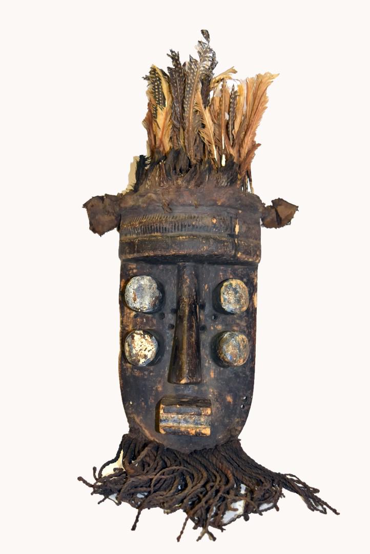 Early African Carved Wood Mask: Carved polychromed wood mask with braided jute beard, cloth and feather decoration; 12.5in.H. x 10in.W.