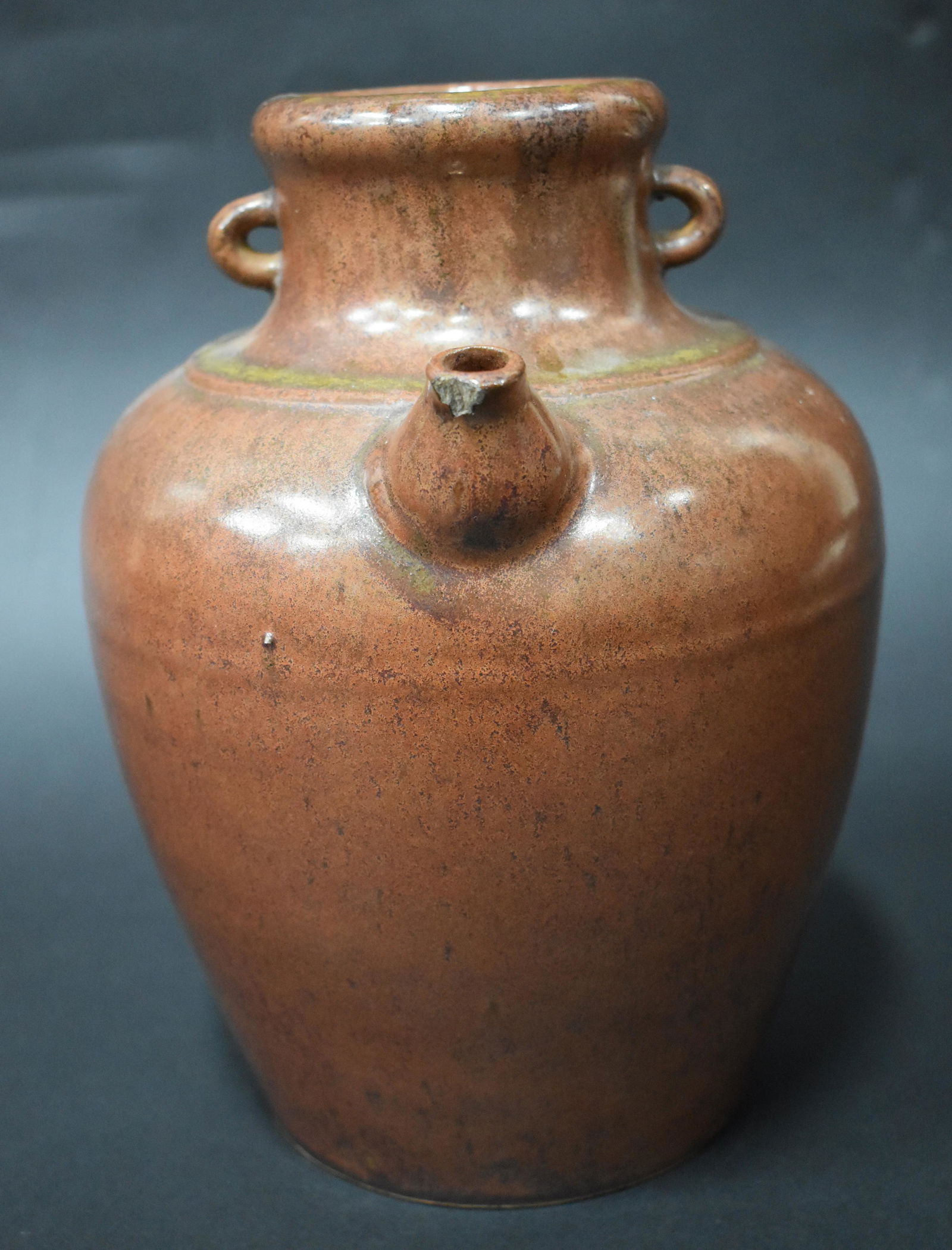 Rare and Imposing Cinnimon Glazed Ming Pot: From the Jian kilns, China, a nice sized lug handled and spouted porcelain water or plum wine pot, 17th century or earlier, with the particularly rare straw blown cinnamon red glaze over a black under