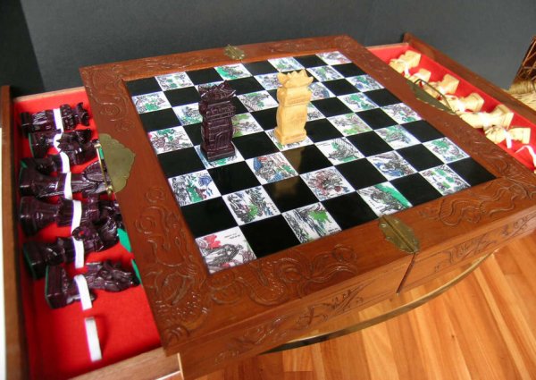 CARVED ORIENTAL CHESS SET: In carved wood box with carrying handle. Opens to tiled chess board. Complete set of hand carved chess pieces located in drawers on each side of box. About 50 years old but hardly used. Size: 18" w x