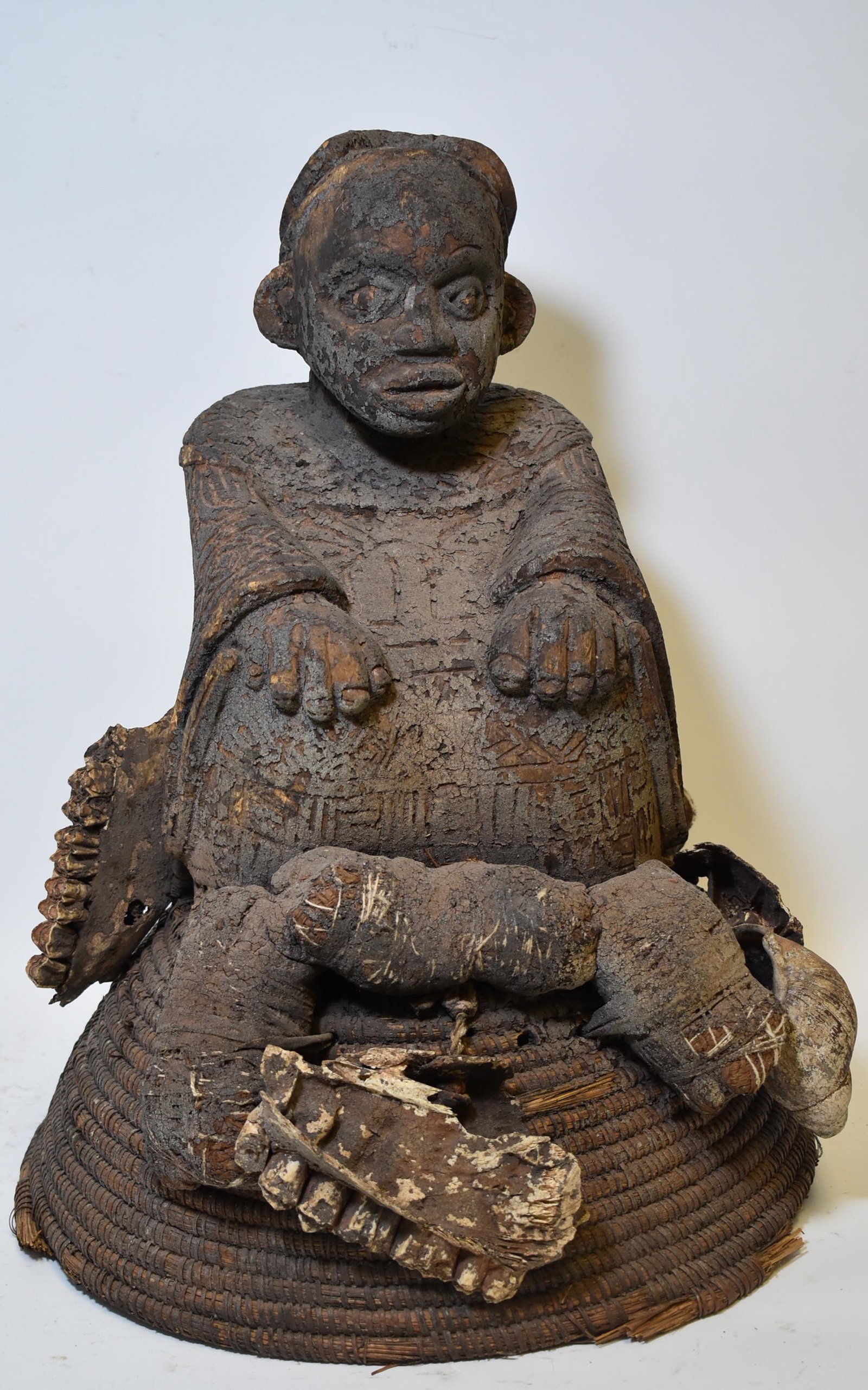 Desireable Unknown Figure. Museum Label: Unknown origin but fascinating combination of things. All elements obviously old. Seated regal type figure on broad basket work base. The basket work has attached magical bundles inc. fractured sectio