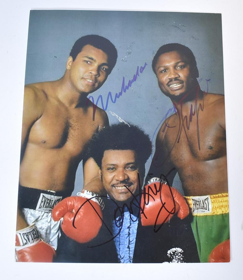Muhammad Ali Autographed Photograph: Autographed color photograph. Ali vs. Frazier publicity photo with promoter Don King. Felt tip pen signatures by all three(3); 9.75in. X 7.75in.
