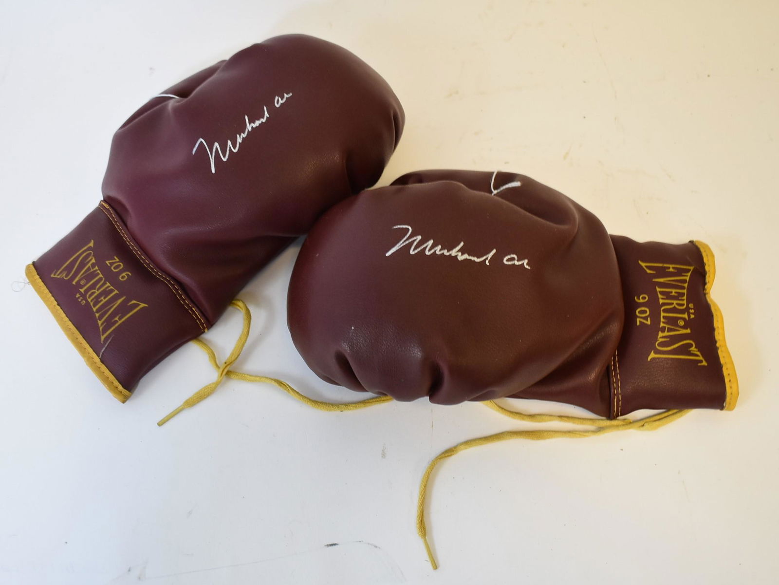 Pair of Muhammad Ali Autographed Boxing Gloves: Pair of autographed boxing gloves. Brown Everlast. 9oz. Silver felt tip marker signatures; 10.5in.`