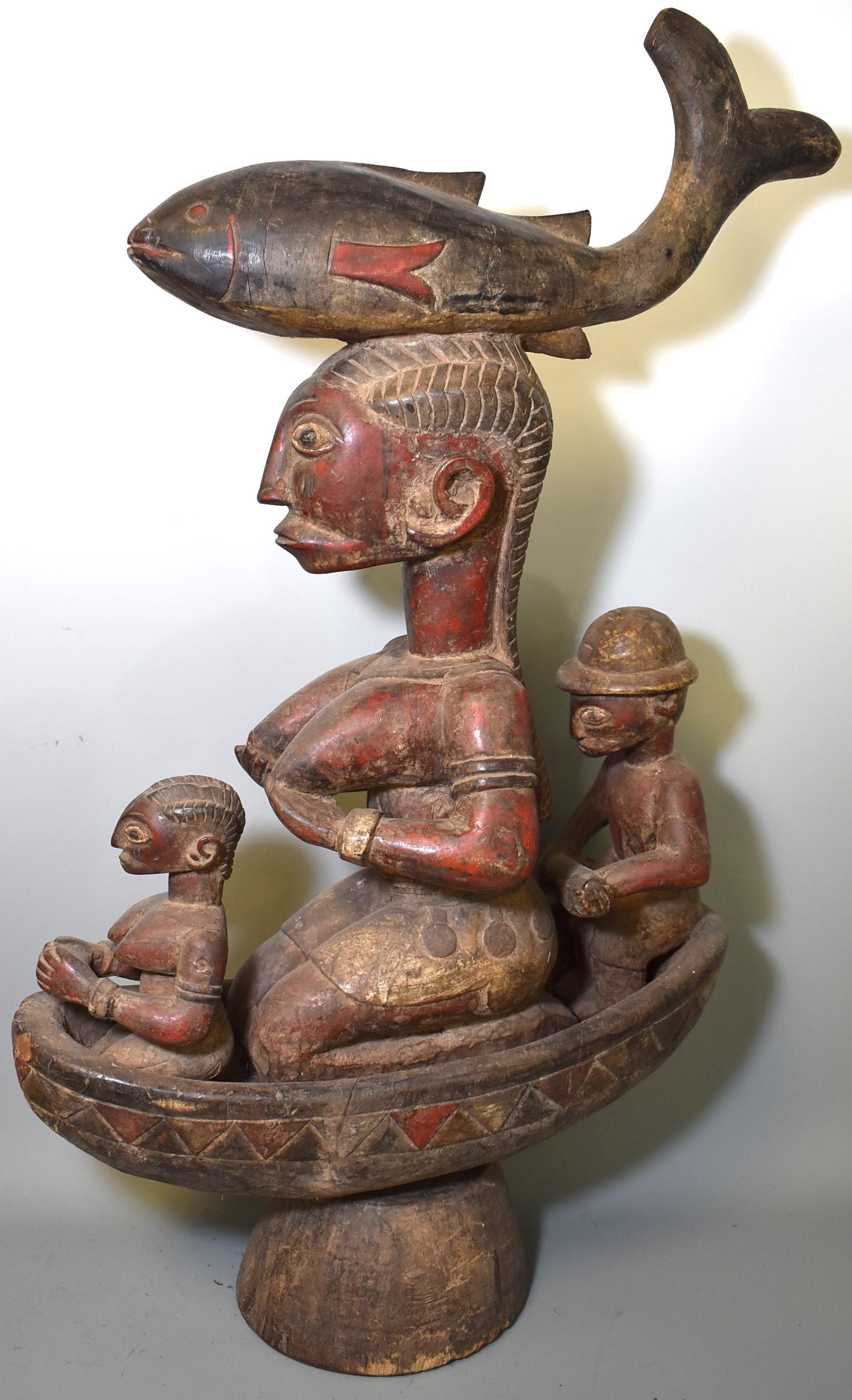 Rare Yoruba Dance Mask Surmount: Exceptional and rare Yoruba dance mask, fish figure crest , a mask surmount . Likely a fisherman's guardian , the goddess holds her breasts , central in the boat with paddler behind and her offshoot a