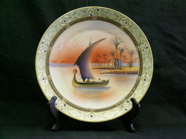 NIPPON SAILBOAT PLATE WITH JEWELS: Hand painted Nippon plate with sailboat, people and "palm" trees. Sunset scene. Jeweled and gilt raised border, blue maple leaf mark.