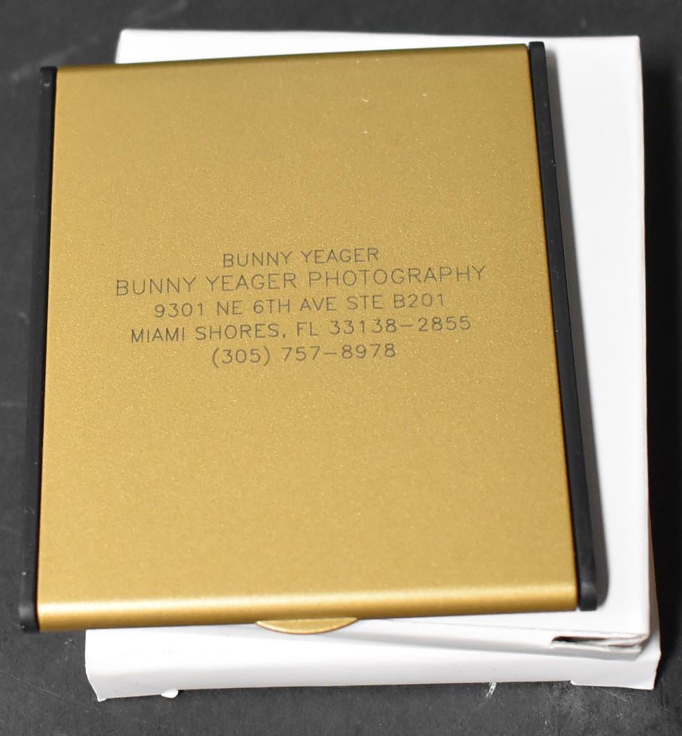 Bunny Yeager Advertising Compact Mirrors (3): Gold toned. Hinged . Advertising print for Bunny Yeager photography shop at the top with address and telephone number. Three in the lot.