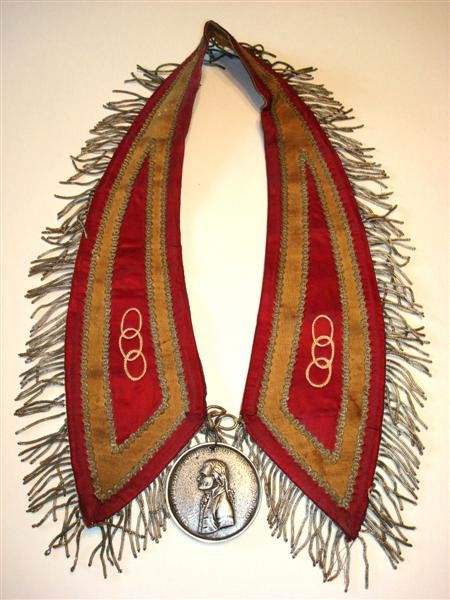 THOMAS JEFFERSON INDIAN PEACE MEDAL: This embroidered fringed neck piece is characterized by three ring emblem on either side. Central area houses a bronze medallion with hand clasp on one side with a tomahawk and peace pipe above and th