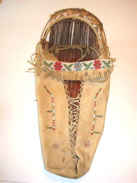 PENOBSCOT INDIAN CRADLE BOARD: Penobscot Indian cradle board, C. 1890-1920. From the upper Maine to lower Canadian region. Authenticated by the reservation head at Fort Kent, Maine. Floral and geometric beadwork. 24" L.