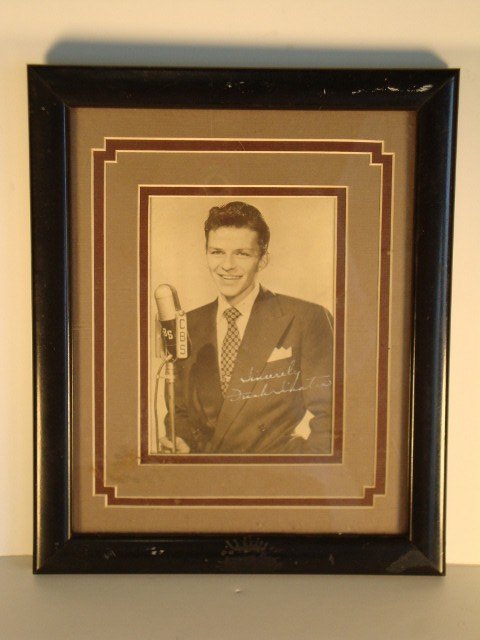 FRANK SINATRA SIGNED PHOTOGRAPH: Young Frank Sinatra, "The Crooner" before a CBS microphone. Signed in white ink, "Sincerely, Frank Sinatra" Framed in black beneath an art deco mat. 4-1/2" x 6" (image) 9" x 11" overall size