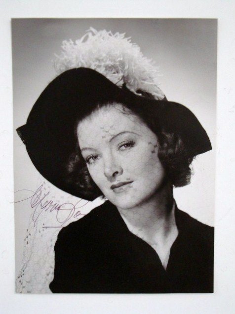 CLARENCE S. BULL PHOTO-MYRNA LOY SGD.: Signed in blue ink Myrna Loy. Back stamp for Clarence S. Bull and MGM. Partial Dell Publishing Stamp. 8 1/4" x 11"