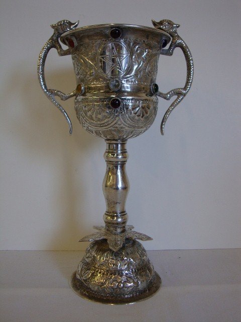 MIDDLE EASTERN SILVER CHALICE: w/ mythological creature handles, highly chased w/ colored and clear glass stones, probably 800 33 troy oz, 12 1/2"H.