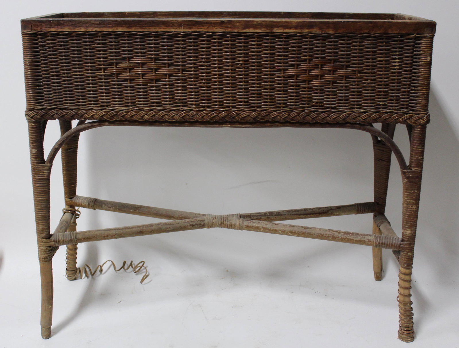 Wicker Planter with Liner. Newburgh NY Company: Wicker Kraft Co. Newburgh, NY marked on a metallic label at the side. With a liner. 10"D. 31 1/4"L:. x 27b 1/2"H.