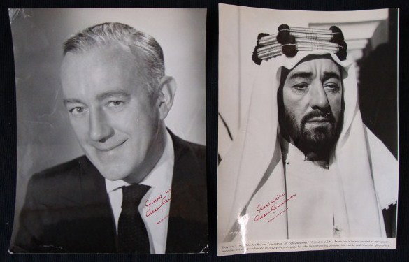 ALEC GUINNESS SIGNED PHOTOGRAPHS (2): Lot of two vintage approximately 7.5 x 9.75 glossy photos, including an original promotional still from Lawrence of Arabia, each signed in red fountain pen, "Good Wishes, Alec Guinness." VF-F