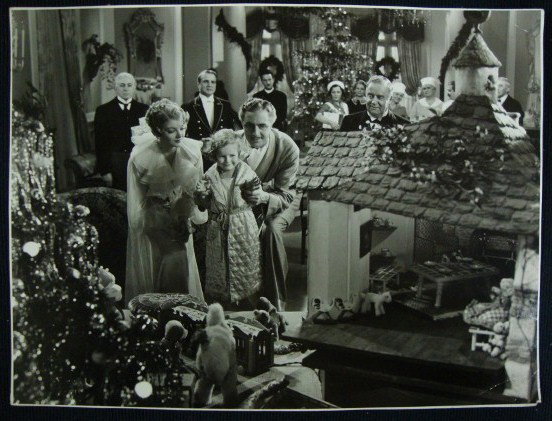 THE GREAT ZIEGFELD PHOTO BY CRONENWITH: Double weight deluxe photo of Myrna Loy, William Powell in a Christmas scene from The Great Ziegfeld. Back stamp for Ed. Cronenwith & MGM. 12 1/2 X 9 1/2. VF-F