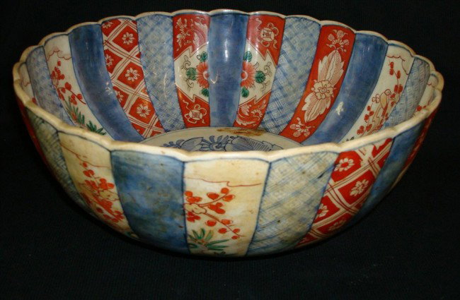 IMARI PORCELAIN PUNCH BOWL: An Imari Porcelain Punch Bowl, Edo Period, c. 1875-85; With fluted sides ornamented with alternating bands of geometric devices and flower sprays in blue, rouge de fer, green and lavender Footed base.