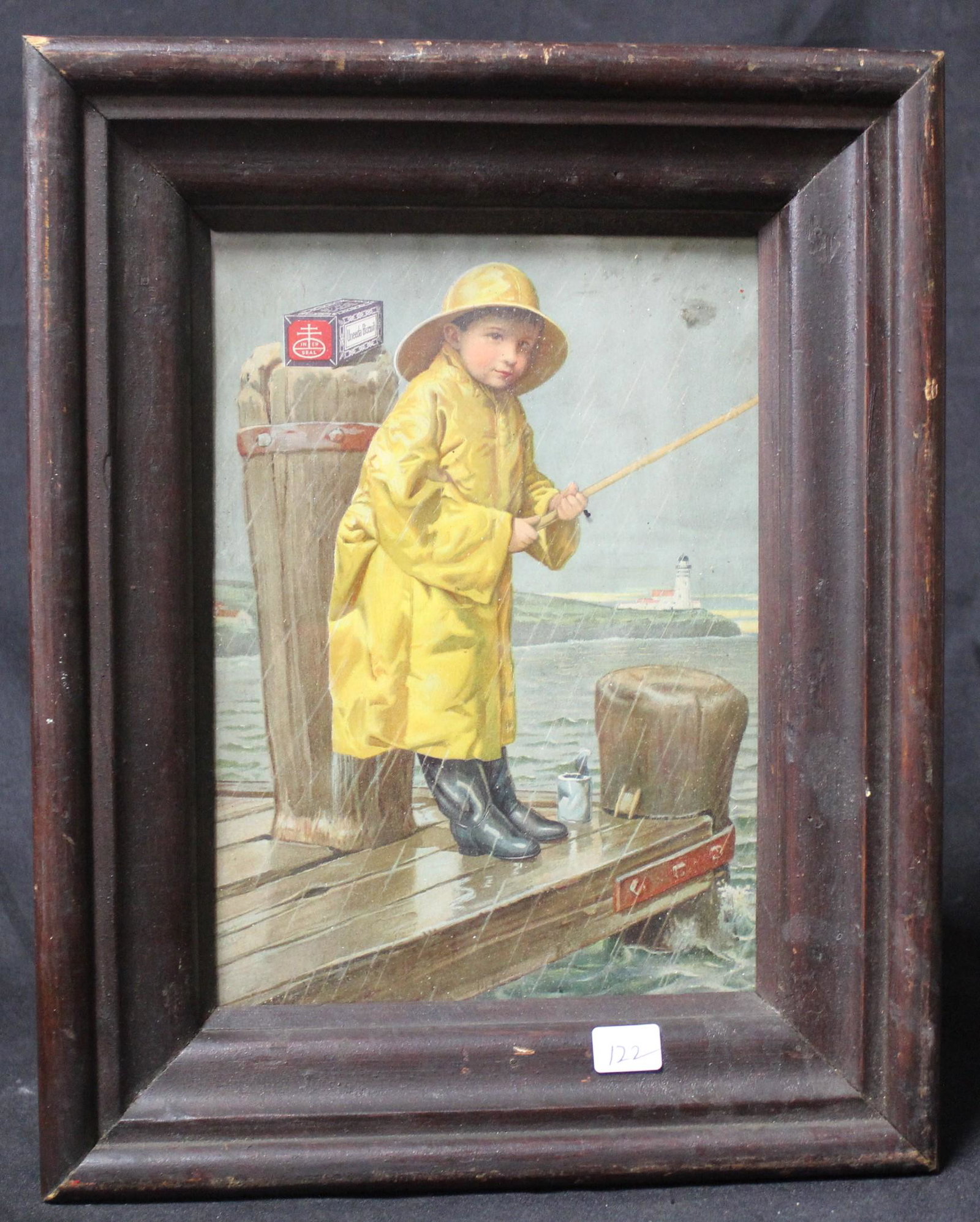 Nabisco Advertising Poster: On paper. Boy fishing in the rain in his rain gear. Product on the pier stand in back of him. Framed in a vintage walnut frame. 9"H. x 6"W (ad itself)