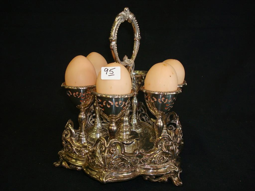VICTORIAN EGG HOLDER WITH CENTRAL HANDLE: Raised on a four footed base. 9" H.