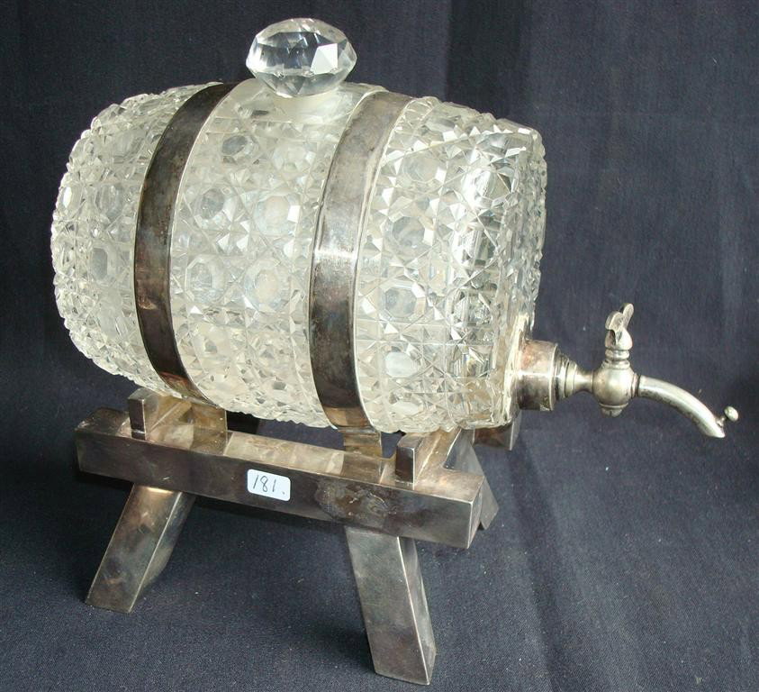 CUT GLASS BARREL SHAPED DECANTER ON STAND: With silver plate bands, stand and spigot. The lot is accompanied by Kirby, Beard and Co. Paris shot glasses probably silverplate