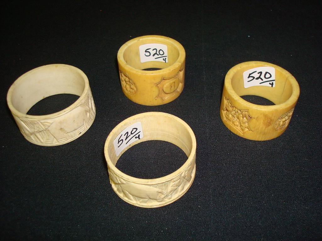 FOUR CARVED IVORY NAPKIN RINGS: Ranging from 1-1/2" diameter to 2" diameter. Elephant motif, Oriental scenes with figures.