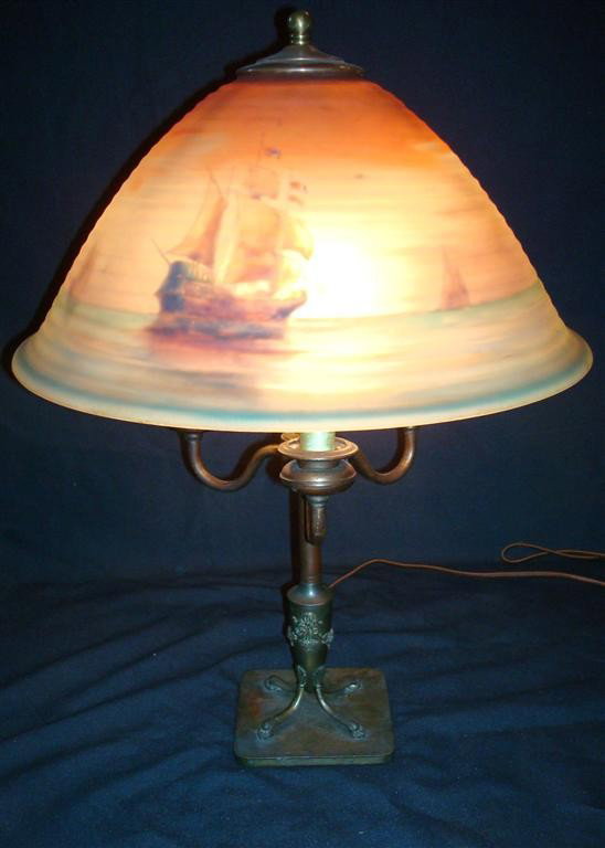 PAIRPOINT REVERSE PAINTED TABLE LAMP: Marine scene. Ships at sea at sunset. Ribbed shade. Artist sgd. G. Morley On a three light candelabra base. Signed on the shade and on the base. . 15: D. shade. 21"H.