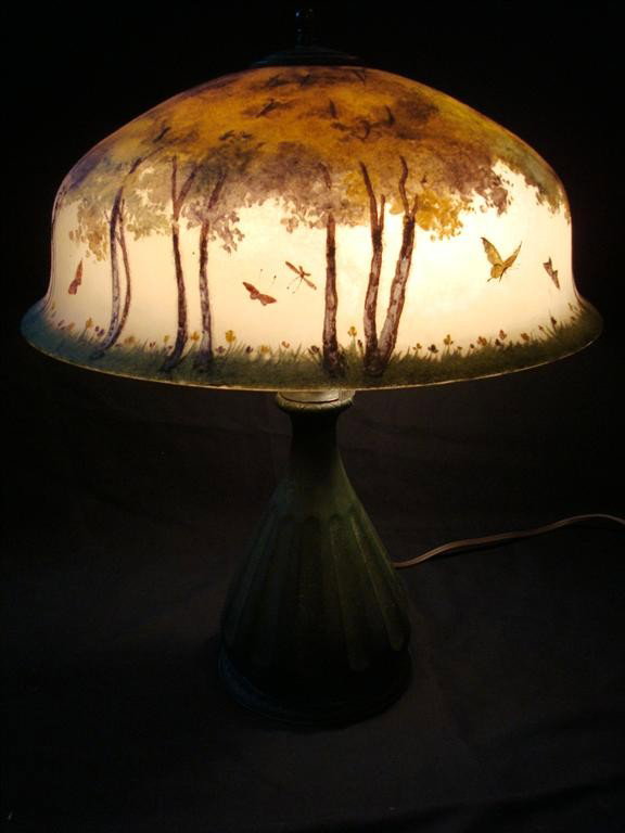 REVERSE PAINTED PAIRPOINT TABLE LAMP: Forest with meadow beneath and butterlies in flight. Decorated on the outside(,chipped ice effect on the outside) and the inside. Signed on the base and #'d D5222 18" D. to the shaped shade. 23"H.