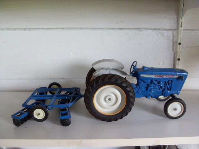 FORD 4000 TRACTOR AND TILLING ATTACHMENT: Blue and grey Ford 4000 tractor (with some paint and decal loss) with a pull-behind tilling attachment. Manufactured by the Ertl Co., Dyersville, Iowa. Made in USA. Tractor is 11" long; tilling attach