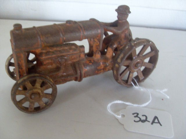 EARLY CAST IRON TRACTOR WITH FARMER: Early cast iron tractor with farmer. Cast iron wheels. Possibly a Ford. Rust with some original orange paint. 5-1/4" long