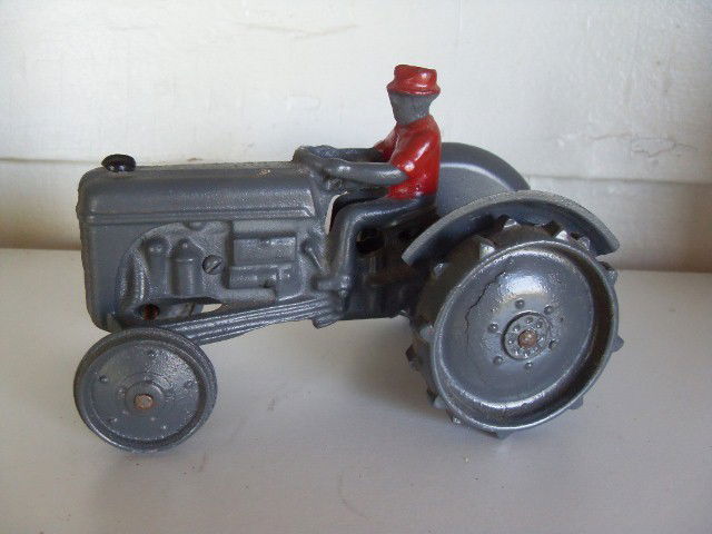 CAST IRON FORD TRACTOR: Grey painted cast iron Ford tractor with figure in painted red hat and shirt. Impressed Made In USA, Arcade. 6-1/2" long.