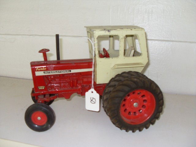 TURBO INTERNATIONAL FARMALL 1456 TRACTOR: Red Turbo International Farmall 1456 tractor with off-white covered cab. Double rear wheels. Front tires marked 1100-16. Some paint loss. 10" long