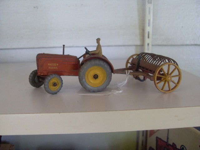 MASSEY-HARRIS TRACTOR & HAY FORK: Red Massey-Harris tractor with die-cast farmer pulling a red hay fork with yellow wheels. Both are marked Dinky Toys, Massey-Harris, Made in England, Meccano Ltd. 6-1/2" long when attached.