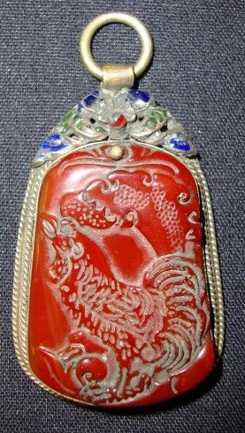 SILVER AND MIXED METAL MOUNTED PENDANT: Carved carnelian plaque mounted on a mixed metal and enameled holder; 2.75in. L. x 1.5in. W.