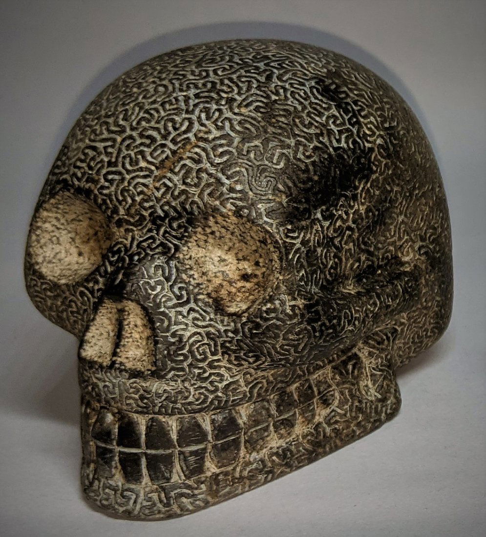 Rare Unique Taino Stone Etched Skull: That of a Zemi or human representation, the surface carved all over, except teeth, nostrils, eyes and underside, in a tight endless squiggle pattern. Of a very tight grained granite like stone. A grue