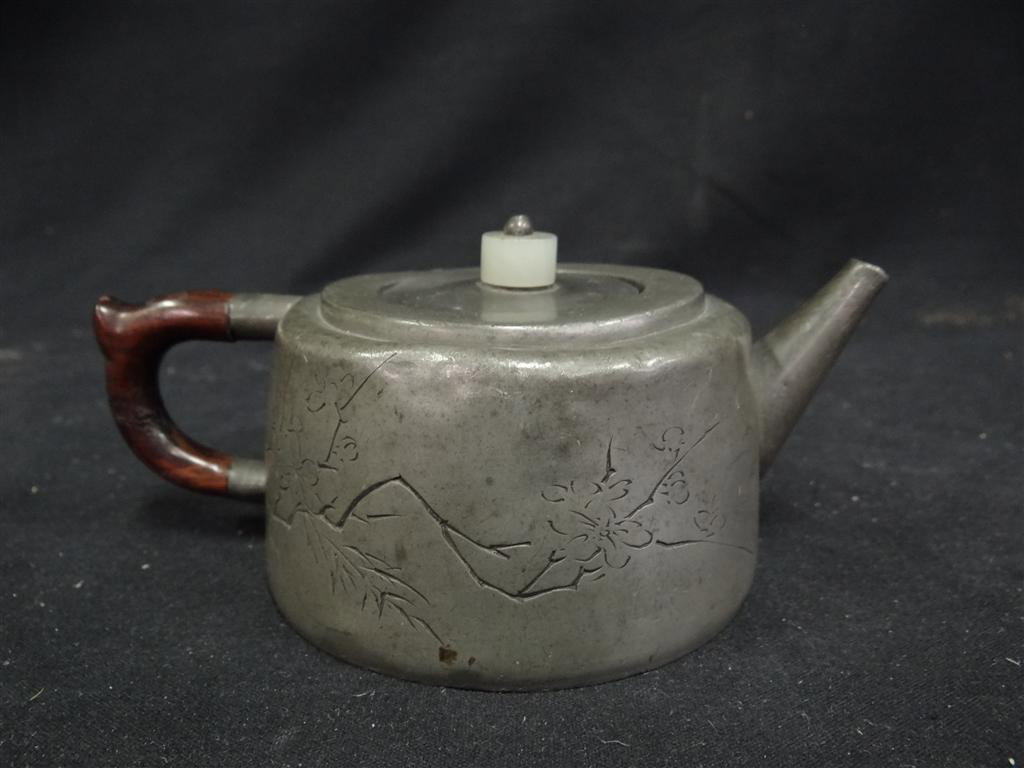 CHINESE PEWTER TEAPOT: Character decorated on one side, lotus blossom on the other. Inscribed rosewood handle. Jade finial 6 1/2"W. x 3 1/2: H.