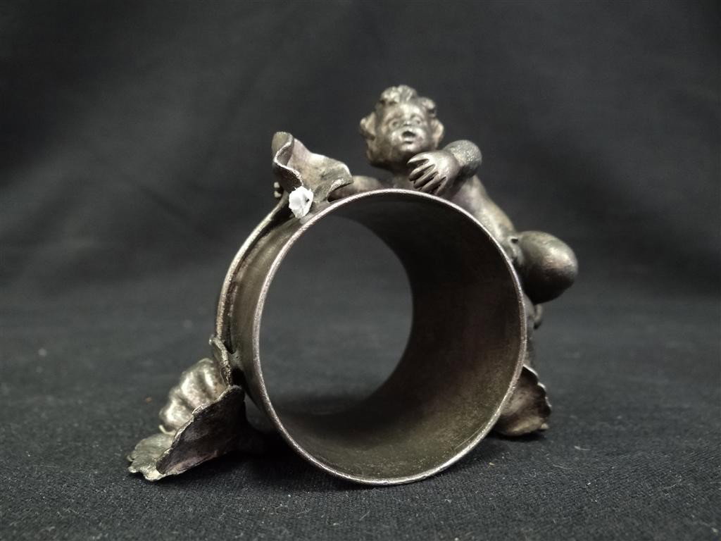 FIGURAL NAPKIN RING: American Victorian silverplate. Cherub tries to climb the flower adorned napkin ring Wilcox