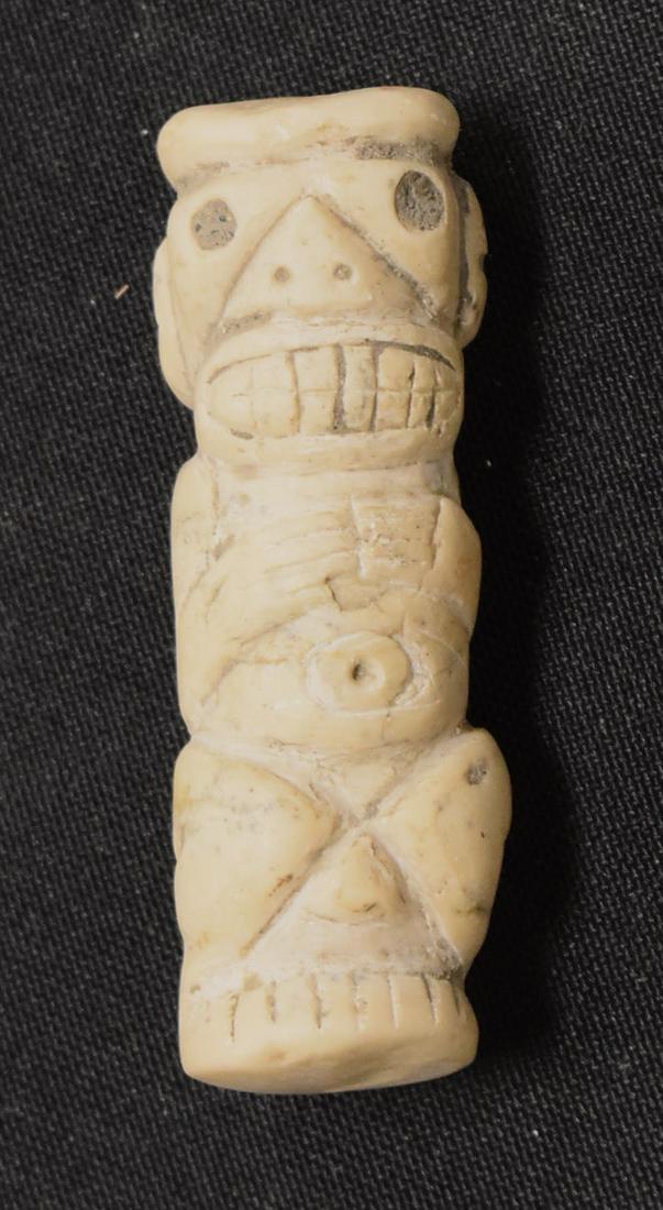 Large Dynamic Taino Figural God Pectoral: Particularly large and impressive, a seated Taino God figureof exceptional merit. Bug eyes with a comically bared rack of teeth, he holds his hands to his chest. Of a nice white stone, bow drilled thr